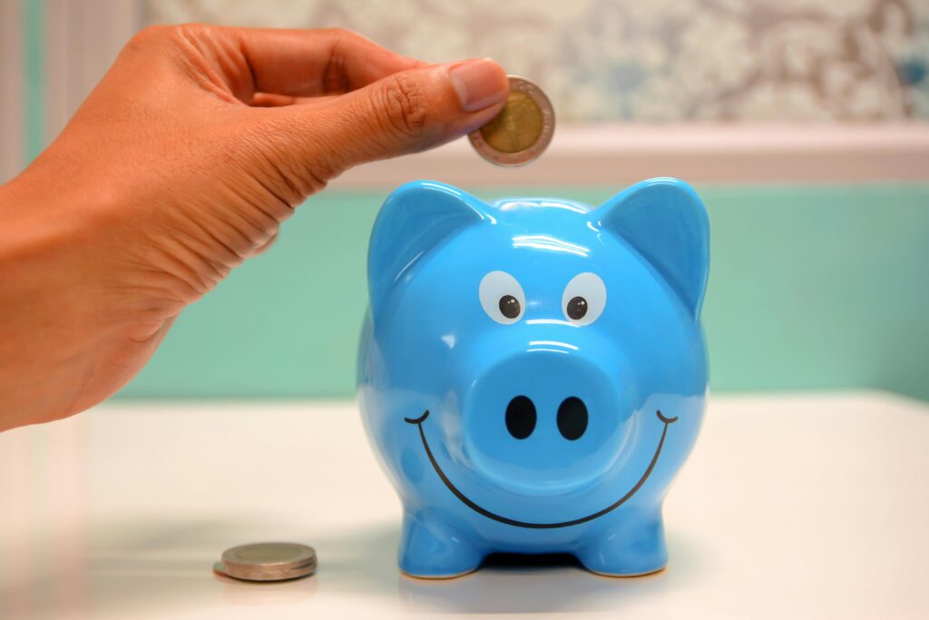 Kiambu Launches New Digital Youth Innovation Hub in Thika Town Hand inserting a coin into a blue piggy bank for savings and money management.
