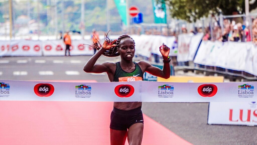 A female athlete triumphantly finishes a marathon race in Lisbon, showcasing determination and endurance.