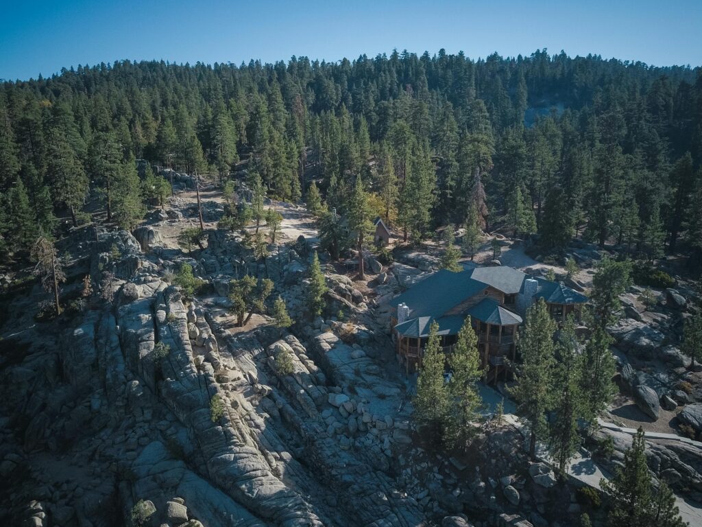 Nyeri to Develop Mount Kenya Eco-Tourism Circuit for Local Communities A scenic aerial shot of a forested area with a lodge nestled among rocky terrains, captured in daylight.